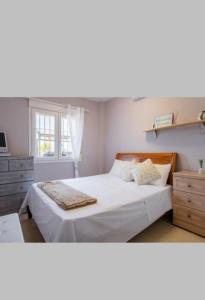 Un dormitorio con una cama con sábanas blancas y una ventana. en The Beach house, en El Verger