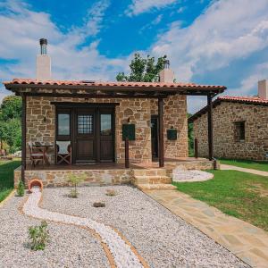 a stone house with a wooden door and a patio at Μαγεμένο Δάσος Apartments in Neokhórion
