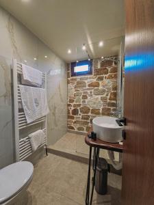 a bathroom with a sink and a stone wall at Μαγεμένο Δάσος Apartments in Neokhórion