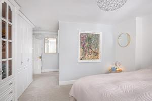 スタンステッド・マウントフィーチェットにあるStylish 3-Bed Home Close to Stansted Airportのベッドと鏡のある白い寝室
