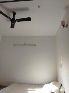 Habitación blanca con ventilador de techo y cama en Abimayu Gardern, en Covelong