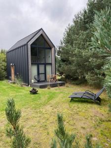 a small black house in a yard with a bench at Stylish Tiny Cabin Pitrog in Pitragutsiyeme