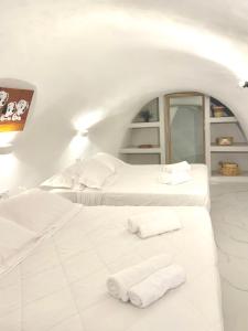 Petuna Cave Suites في فيرا: سريرين في غرفة بيضاء عليها مناشف