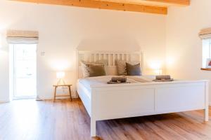 1 cama blanca en un dormitorio blanco con suelo de madera en Ferienwohnung Hanna, en Steinbergkirche