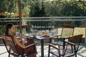 une femme assise à une table sur un patio dans l'établissement Amenity Hotel & Resort Orlické hory, à Deštné v Orlických horách