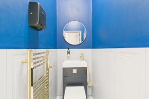 ein blaues Bad mit einem WC und einem Spiegel in der Unterkunft Host & Stay - Bellevue Luxe in Redcar