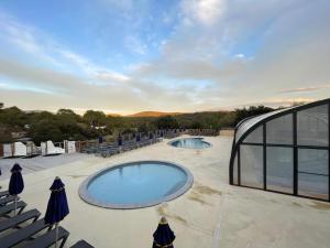 two swimming pools on a patio with chairs at Bungalow au pied des gorges de Baudinard à Montagnac-Montpezat in Saint-Laurent-du-Verdon