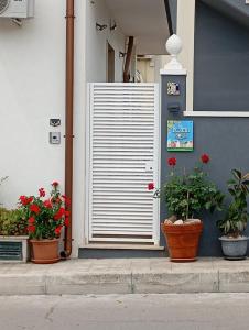 Una puerta de persiana blanca en el costado de un edificio con plantas. en B&B Nonna Rosa, en Castellaneta
