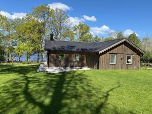 a house on a grassy field with a tree at Lake & Forest Escape in Skeinge in Osby