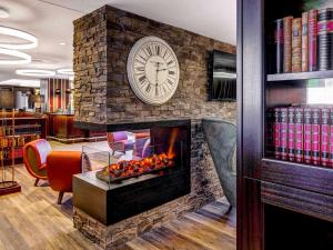 einen Kamin in einer Bibliothek mit einer Uhr an der Wand in der Unterkunft Aparthotel Adagio Frankfurt City Messe in Frankfurt am Main