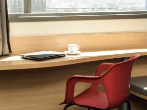 a red chair sitting next to a desk with a laptop at ibis Rio Porto Atlantico in Rio de Janeiro +41 photos