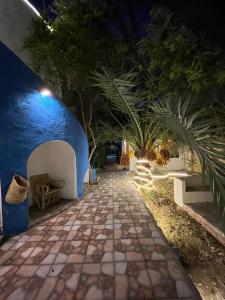 a walkway with a blue wall and a palm tree at Bait Gamal Siwa بيت جمال سيوة in Siwa