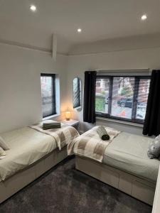 two beds in a room with two windows at Beach Hill House - Rhos on Sea in Colwyn Bay