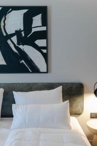a bedroom with a white bed with a painting on the wall at Conlon House Lower East Side in Munich