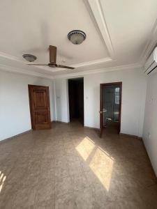 une chambre vide avec un ventilateur de plafond et une porte dans l'établissement Joyreign residence, à Accra