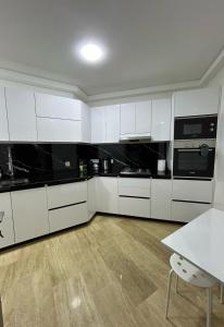 a kitchen with white cabinets and a table in it at Modern 2BR Apartment Tangier Center with Air Conditioning and WiFi in Tangier