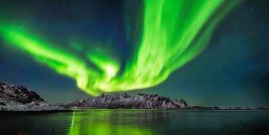 ein Polarlicht am Himmel über einem Gewässer in der Unterkunft Lofot rommet in Svolvær + 8 Fotos
