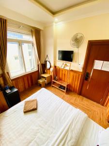 a bedroom with a white bed and a television at Khách Sạn Bình Nguyên Đà Lạt in Da Lat +18 photos
