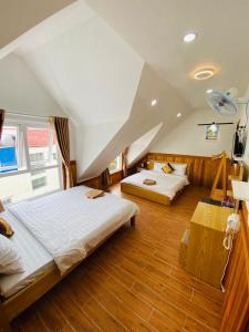 two beds in a room with an attic at Khách Sạn Bình Nguyên Đà Lạt in Da Lat
