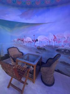 a room with a table and chairs and a painting of flamingos at HV Beach Resort in Mandvi