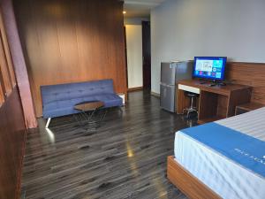 a room with a blue couch and a desk with a computer at Blue Luxury Hotel & Spa in Da Nang