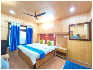a bedroom with a bed with blue curtains and a mirror at Lake View Hotel Chinar Mall Road Nainital - Near NAINA DEVI TEMPLE & NAINI LAKE - FREE WI-FI AND ROOM SERVICE AVAILABLE - PREMIUM HOTEL IN NAINITAL in Nainital +7 photos