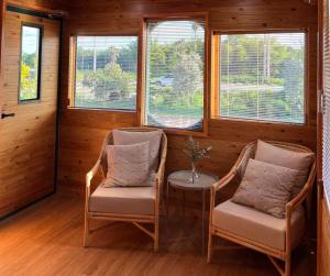 two chairs and a table in a room with windows at SafeHouse resort เซฟเฮ้าท์รีสอร์ท 