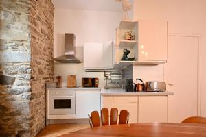 ヴァンヌにあるAppartement Centre Historique Cheminée, Mur en Pierre & Déco Jungleの白いキャビネットとテーブルと椅子のあるキッチン