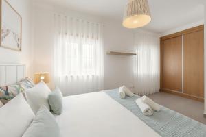 a bedroom with a white bed with towels on it at Route 22 Baleal in Ferrel