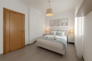 a white bedroom with a bed and a cabinet at Route 22 Baleal in Ferrel