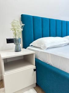 ein Bett mit blauem Kopfteil und einer Vase mit Blumen in der Unterkunft Уютная и светлая квартира в Алматы рядом с метро in Almaty