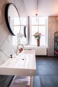 a white bathroom with a sink and a mirror at Will & Tate City Stay in The Hague +42 photos