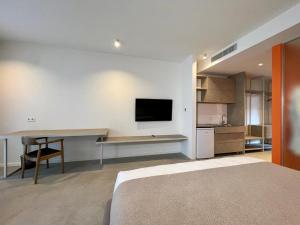 トビリシにあるConcept 1416 apart hotelのベッド、机、テレビのある寝室