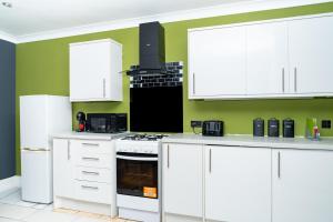 a kitchen with white cabinets and green walls at Elegant 1BD, Gym, Parking, Bus to Airport, Sleeps4 in Edinburgh