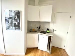 a kitchen with white cabinets and a white refrigerator at New 466 Suite Alain - Cosy Apartment Paris Center in Paris