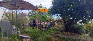 a group of people sitting at a table under an umbrella at Chambres d'hôte A Caserella, Maison de village rénovée avec vue sur mer in Valle-di-Campoloro