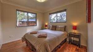 a bedroom with a large bed with two windows at Tiny Away Escape at Granite Belt - Sommerville Valley in Stanthorpe +50 photos