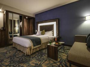 a hotel room with a large bed and a couch at Novotel Yanbu Albahr in Yanbu