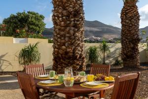 a wooden table with food on it with palm trees at Gonçalves Guest House Patio and Sea View in Porto Santo +29 photos