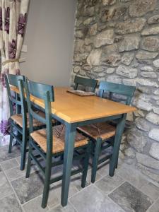 a wooden table with four chairs and a stone wall at Aghavannagh Mountain Lodge in Aghavannagh