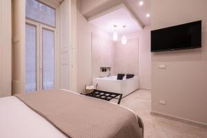 ナポリにあるMadame Toledo Luxury Roomsのベッドと壁掛けテレビのある寝室