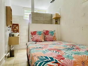 a bedroom with a bed with a colorful comforter at Saline les bains studio avec cuisine & espace détente extérieurs calme & plage à pied in Saint-Paul