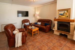 a living room with leather furniture and a fireplace at Hostal Valderas in Valderas