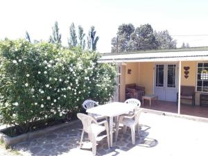 a patio with a table and chairs and a bush at Starry Nights Guest House in Nieu-Bethesda