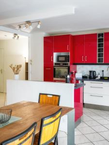 a kitchen with red cabinets and a wooden table at T3 68m2 Garage Terrasse Gare aux portes de Genève in Saint-Julien-en-Genevois