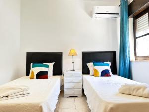 two beds in a room with white walls and blue curtains at Vista Golf by Becherish in Bicas +27 photos