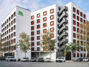 two white buildings with cars parked in front of them at ibis Styles Barcelona City Bogatell in Barcelona