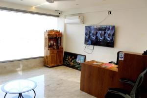a room with a table and a tv on the wall at Aatithya Residency in Alandi