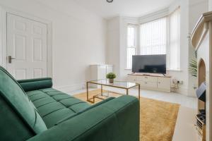 Una sala de estar con un sofá verde y un televisor. en Mersey View 4 Bedroom by Liverpoollux Next To Everton Stadium, en Liverpool 42 fotos más