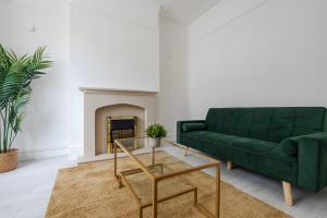 sala de estar con sofá verde y chimenea en Mersey View 4 Bedroom by Liverpoollux Next To Everton Stadium, en Liverpool